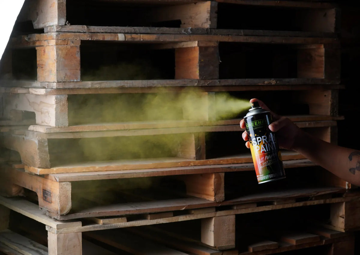 A professional applying Greenfield all-purpose spray paint to timber